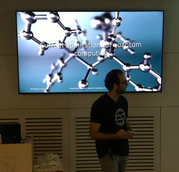 Ahmed lecturing at CERN in front of a slide titled 'Current applications of quantum computing'